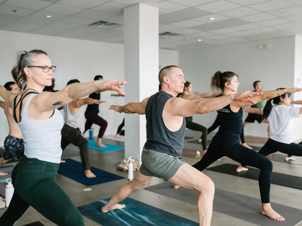 Students holding a standing strength pose during a flow class.