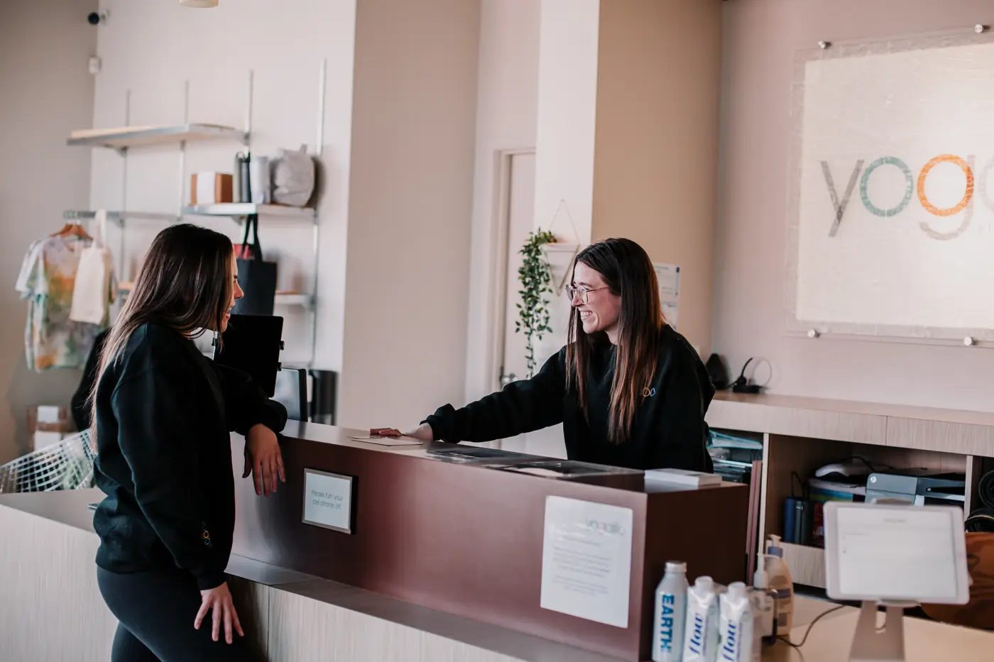 A Yogalife South staff member welcoming a student at the front desk.